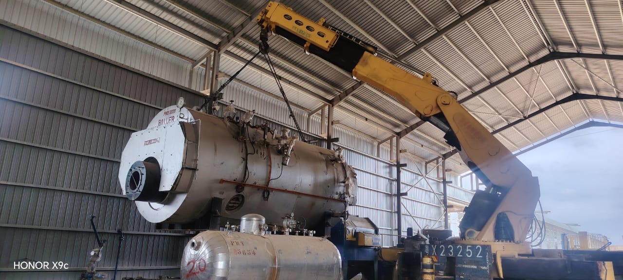 Crane lifting a boiler inside an industrial building