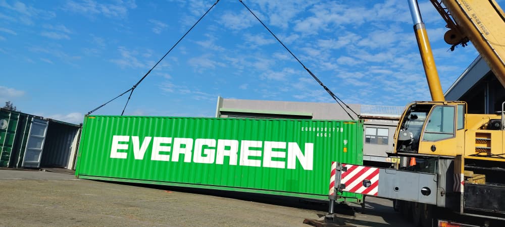 Mobile crane lifting a shipping container in a yard