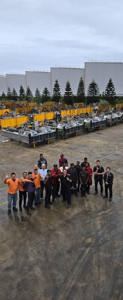Project team standing outdoors beside rows of industrial machinery on site in Taiwan